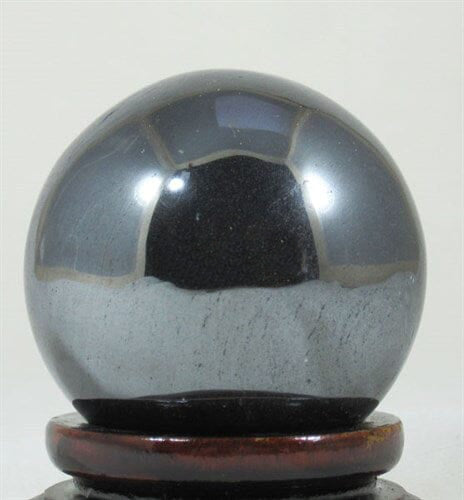 a Haematite sphere on a round wooden crystal stand